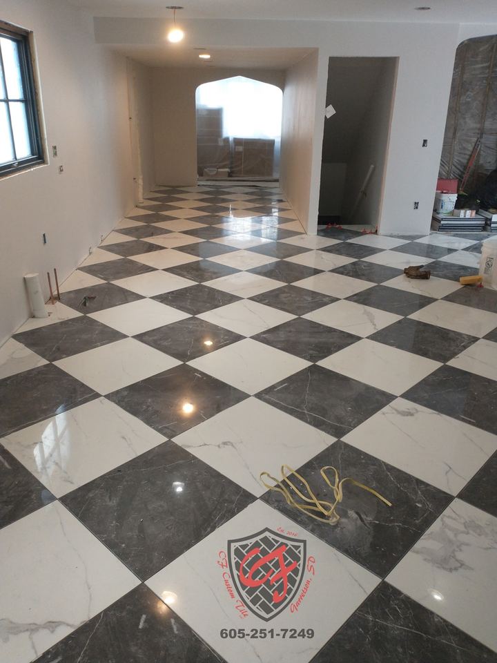 Black and white checkerboard tile floor in a hallway/entry, grout stage
