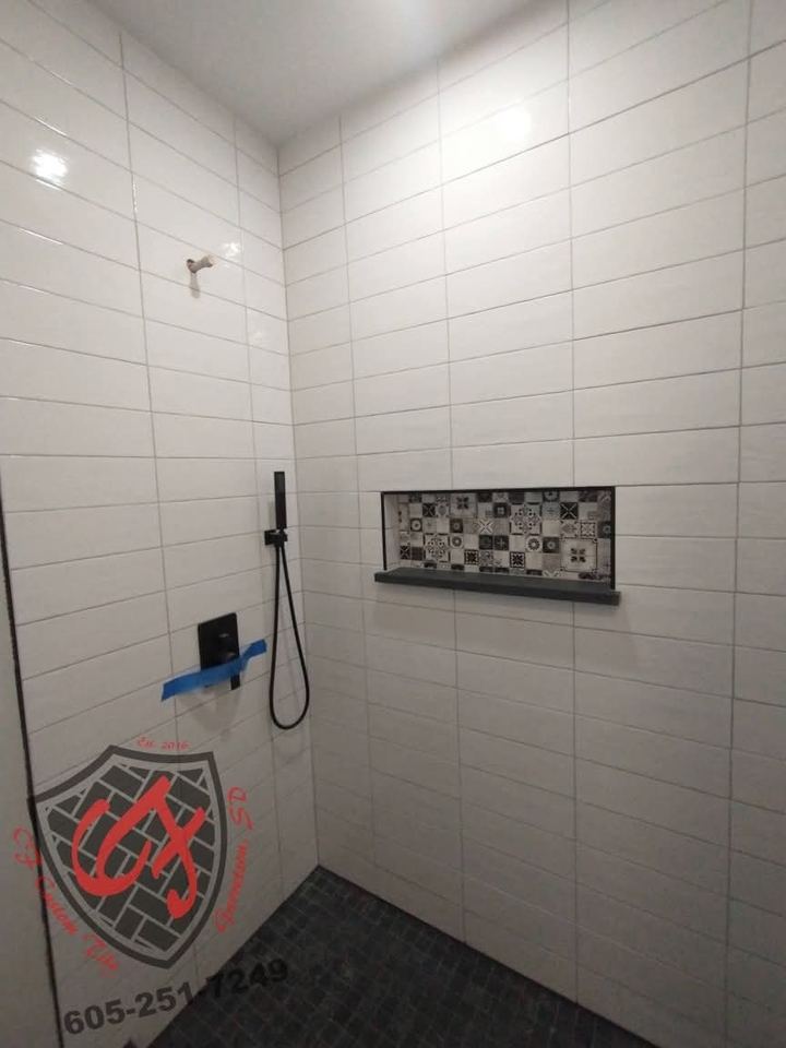 White large-format tile walk-in shower with mosaic niche, black fixtures and dark tile floor